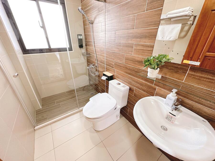 A modern bathroom with a glass-enclosed shower, a toilet, and a sink with a mirror.