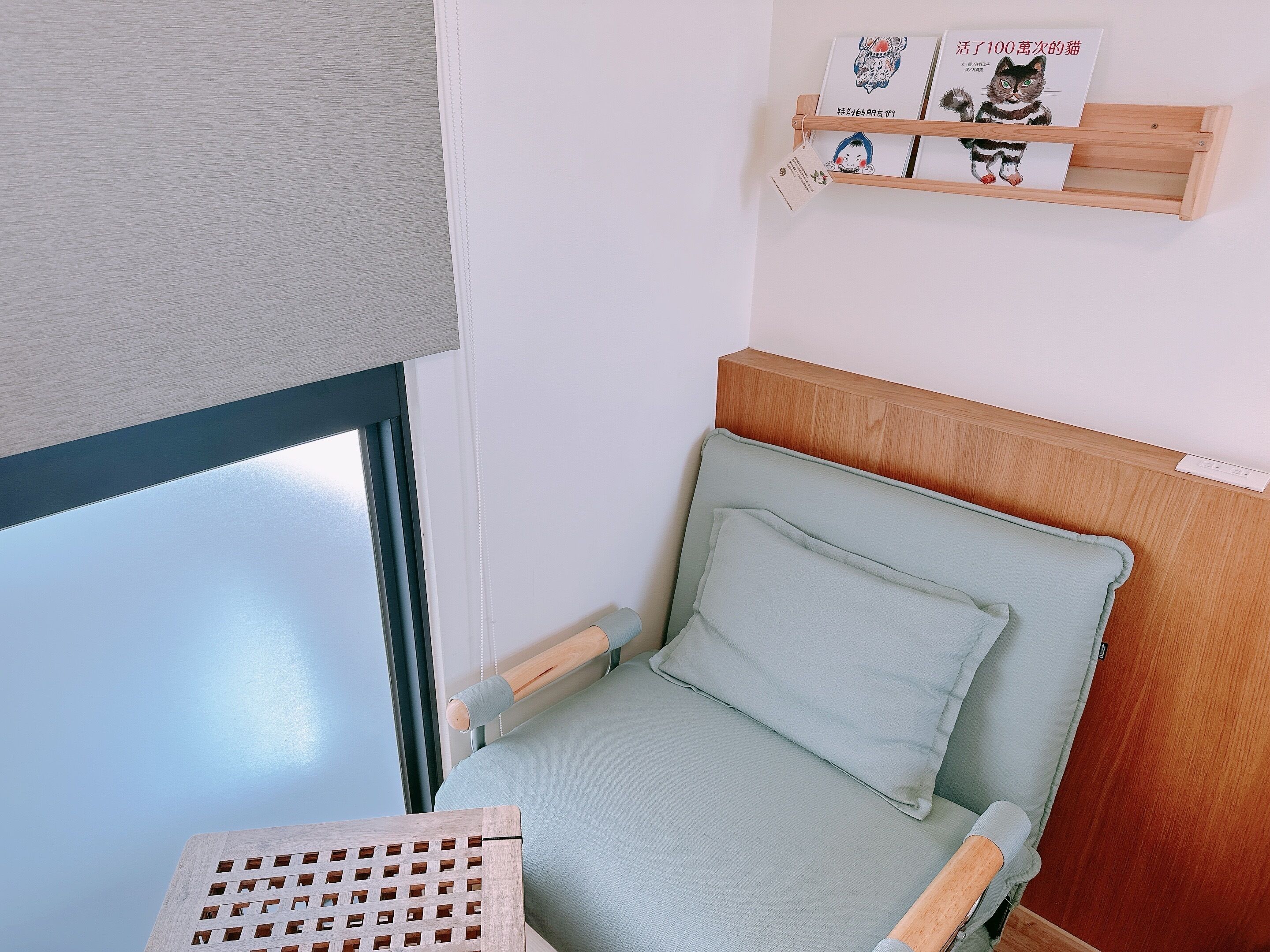 Una habitación pequeña y acogedora con una cama, un cabecero de madera, una estantería con libros y una ventana.