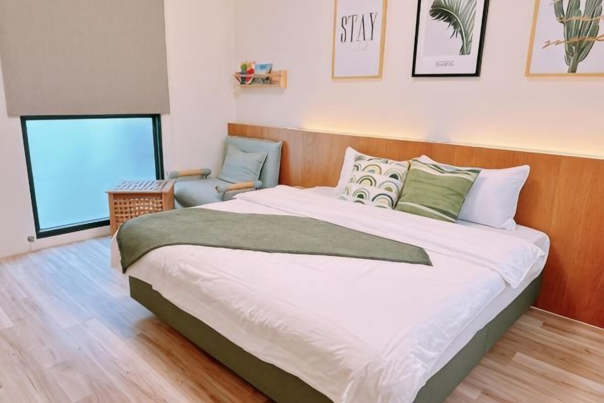 A bedroom with a bed, a chair, a small table, and a window.