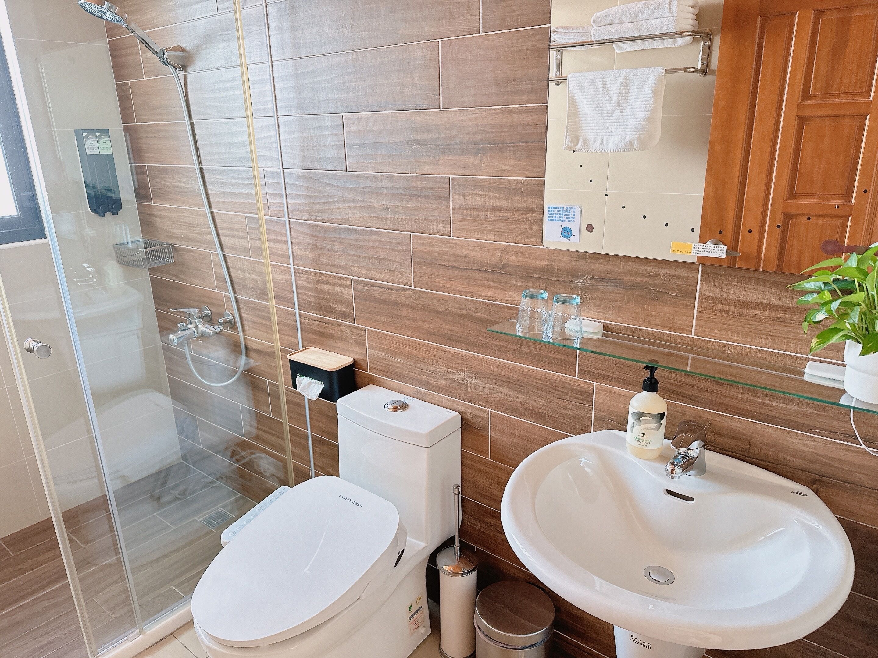 Une salle de bain moderne avec une douche à parois de verre, des toilettes blanches, un lavabo et un meuble-lavabo en bois.