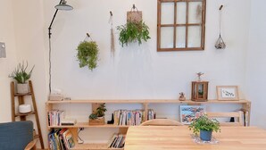 A cozy room with a wooden table, bookshelves, a desk, and various plants. - Gardenstay (Luodong)