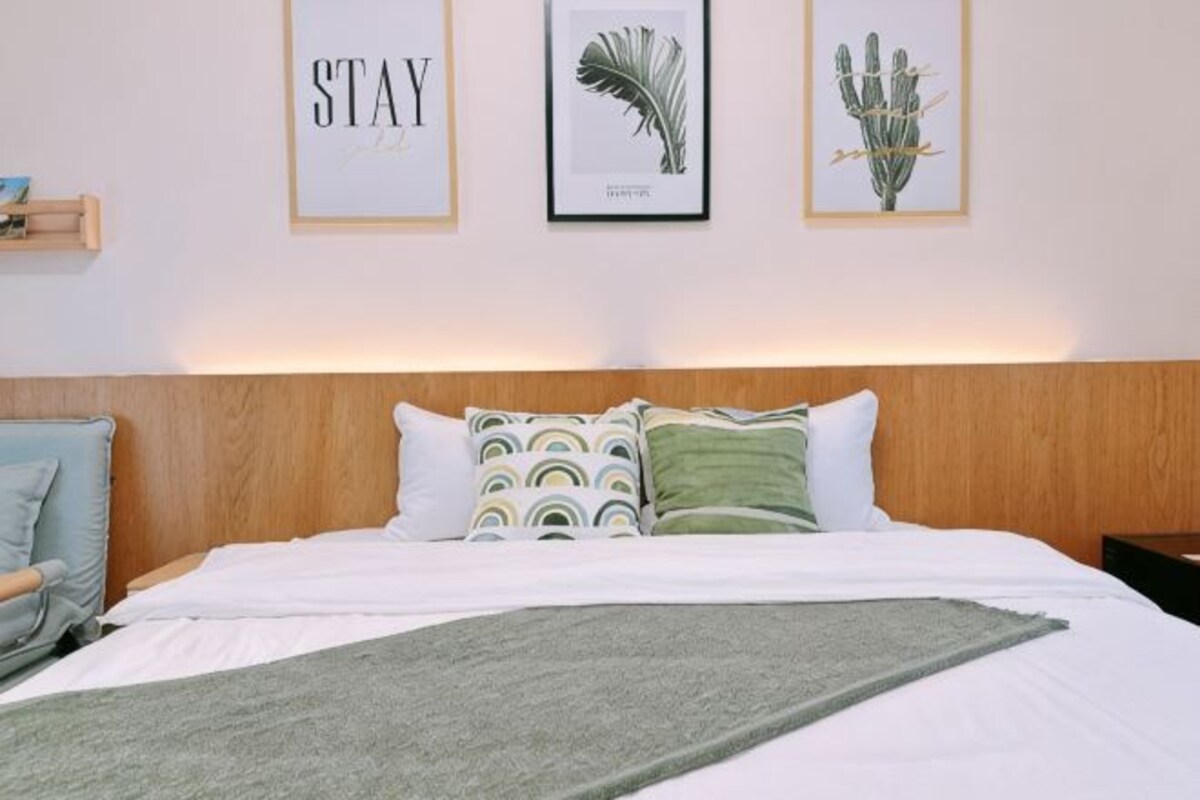 A neatly made bed with pillows and a blanket, a wooden headboard, and three framed pictures on the wall.