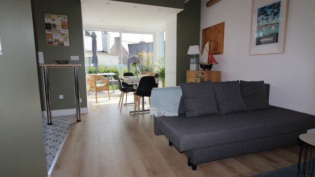 Una sala de estar con un sofá gris, una mesita y un comedor con mesa y sillas.