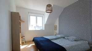Un dormitorio con cama, ventana, lámpara colgante y pared con diseño.