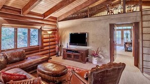 A log cabin interior with a wooden ceiling, a television, leather furniture, and a staircase leading to an upper level. - Eagles Nest Luxury Retreat, Views, Hot Tub, Walking distance to Resort (Sundance)