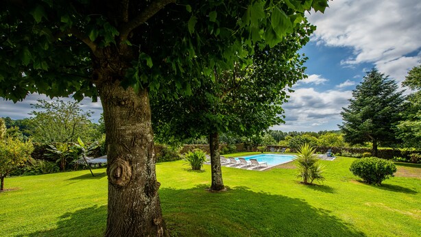 A well-maintained lawn with a swimming pool, surrounded by trees and shrubs. - The noble house of Luroa built in 1505. (Cambo-les-Bains)