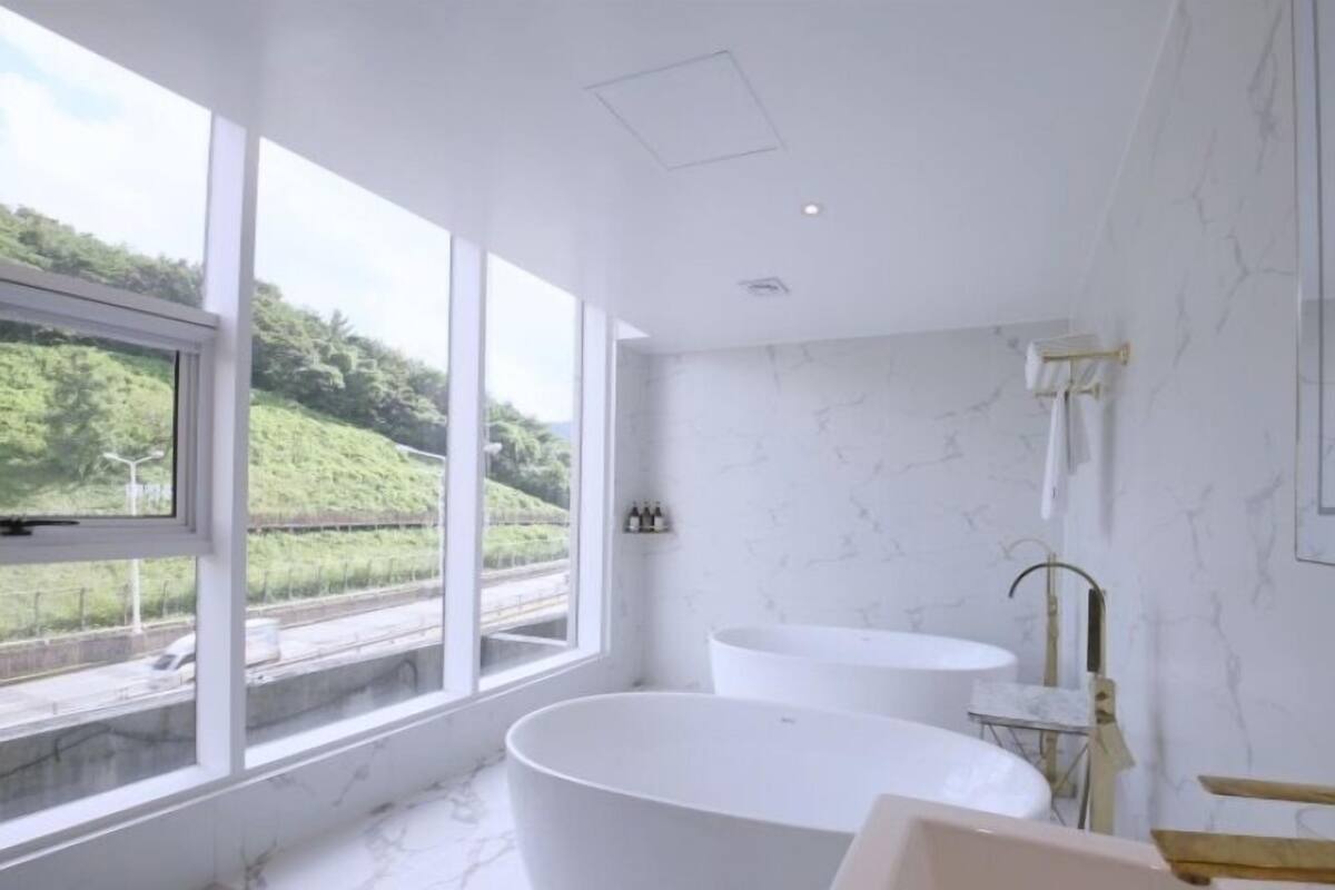 A modern bathroom with a freestanding bathtub, a small sink, and a shower area.