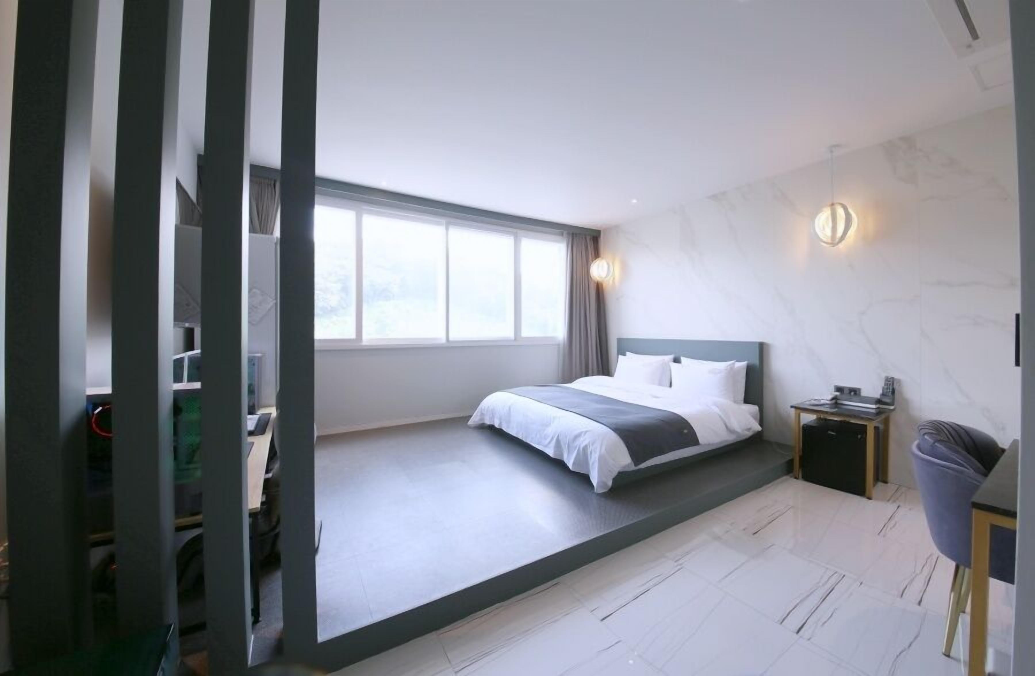 A modern bedroom with a bed, a desk, and a chair.