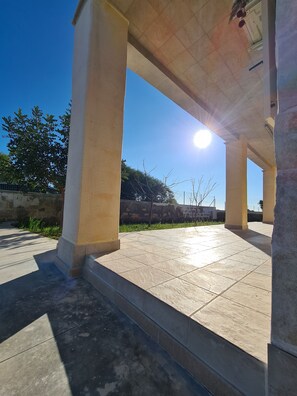 An outdoor covered area with tiled flooring and columns, under a clear sky with the sun shining. - Beautiful villa near Torre Ovo, 800 meters from the sea.  (Monacizzo-librari-truglione)