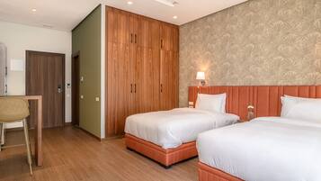 Une chambre d’hôtel avec deux lits, un bureau et une chaise.