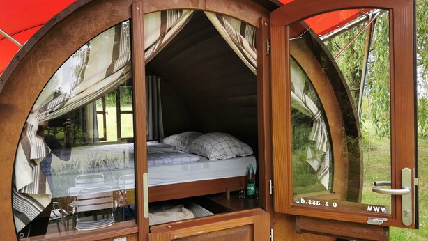 A cozy, circular wooden room with a bed, a small table, and a mirror.