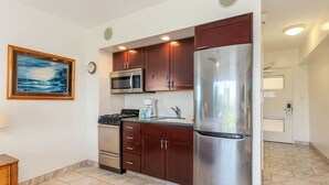 A modern kitchen with stainless steel appliances, wooden cabinets, and a tiled floor.