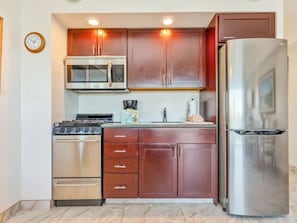 Una cocina moderna con electrodomésticos de acero inoxidable, armarios de madera y un microondas integrado.
