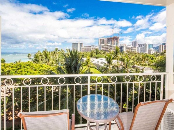 A balcony with a view of a cityscape and palm trees.