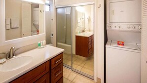 A bathroom with a sink, mirror, and a walk-in shower.