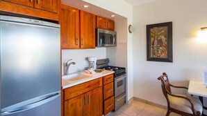 A kitchen with wooden cabinets, stainless steel appliances, and a dining area with a chair and table.