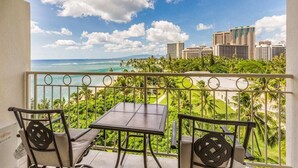 A balcony with a table and chairs, overlooking a cityscape and ocean. - Modern Ocean View W/Lanai and A/C - Waikīkī Shore #704 (HONOLULU)