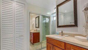 A modern bathroom with a vanity, a large mirror, and a walk-in shower. - Modern Ocean View W/Lanai and A/C - Waikīkī Shore #704 (HONOLULU)