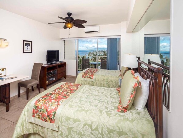 Une chambre d’hôtel avec deux lits, un bureau, une télévision et un balcon avec vue.