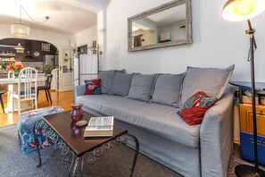 A living room with a sofa, a coffee table, a lamp, and a mirror.
