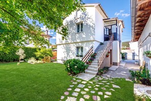 A modern two-story house with a well-maintained lawn and a stone pathway leading to the entrance. - Cozy Home With Private Garden (Jelenje)