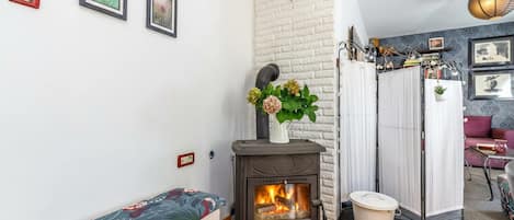 A cozy room with a wooden bench, a fireplace, and a white brick wall.