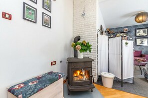 A cozy room with a wooden bench, a fireplace, and a white brick wall. - Cozy Home With Private Garden (Jelenje)