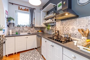 A kitchen with white cabinets, a built-in stove, and a window with curtains.