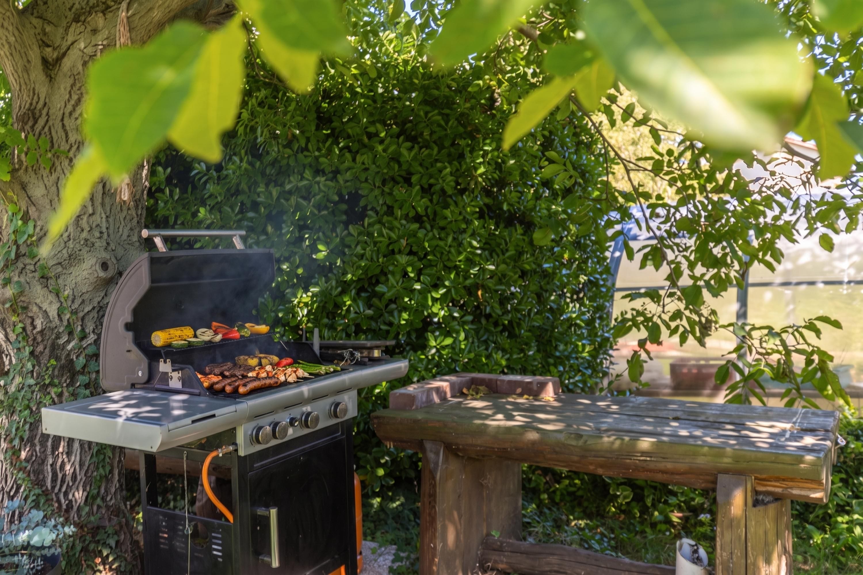 An outdoor grill with various foods being cooked, surrounded by greenery and a wooden bench.