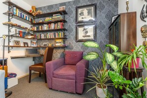 A cozy reading nook with a purple armchair, bookshelves, and framed artwork.