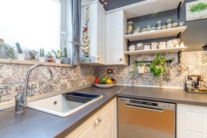 A kitchen with a dishwasher, a sink, and a window with plants. - Cozy Home With Private Garden (Jelenje)
