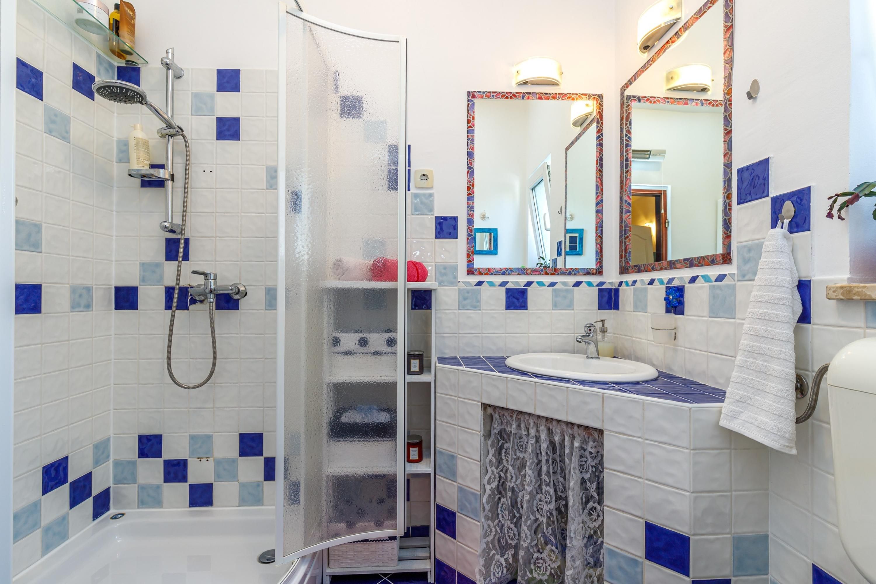 Un bany amb dutxa, un lavabo, un vàter i un mirall.