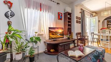 Se ve una sala de estar con televisor, un comedor y una cocina a través de una puerta abierta.