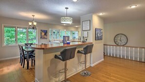 Une cuisine moderne avec un coin bar, un plancher en bois et de grandes fenêtres.