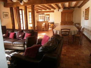 A rustic interior with a leather sofa, wooden dining table, and exposed beams.