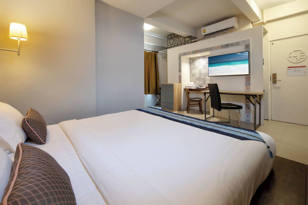 A hotel room with a bed, a desk, and a TV.