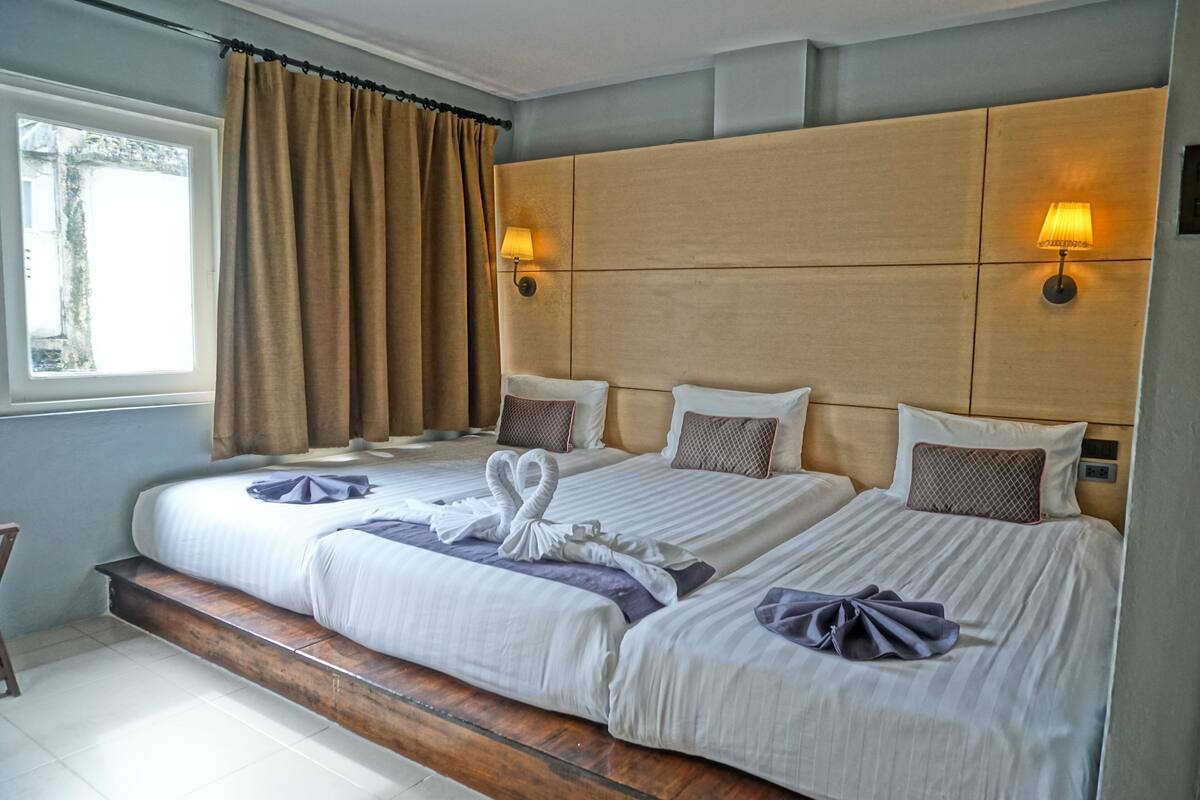 A hotel room with two beds, wooden headboards, and bedside lamps.