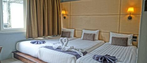 A hotel room with two beds, wooden headboards, and bedside lamps.