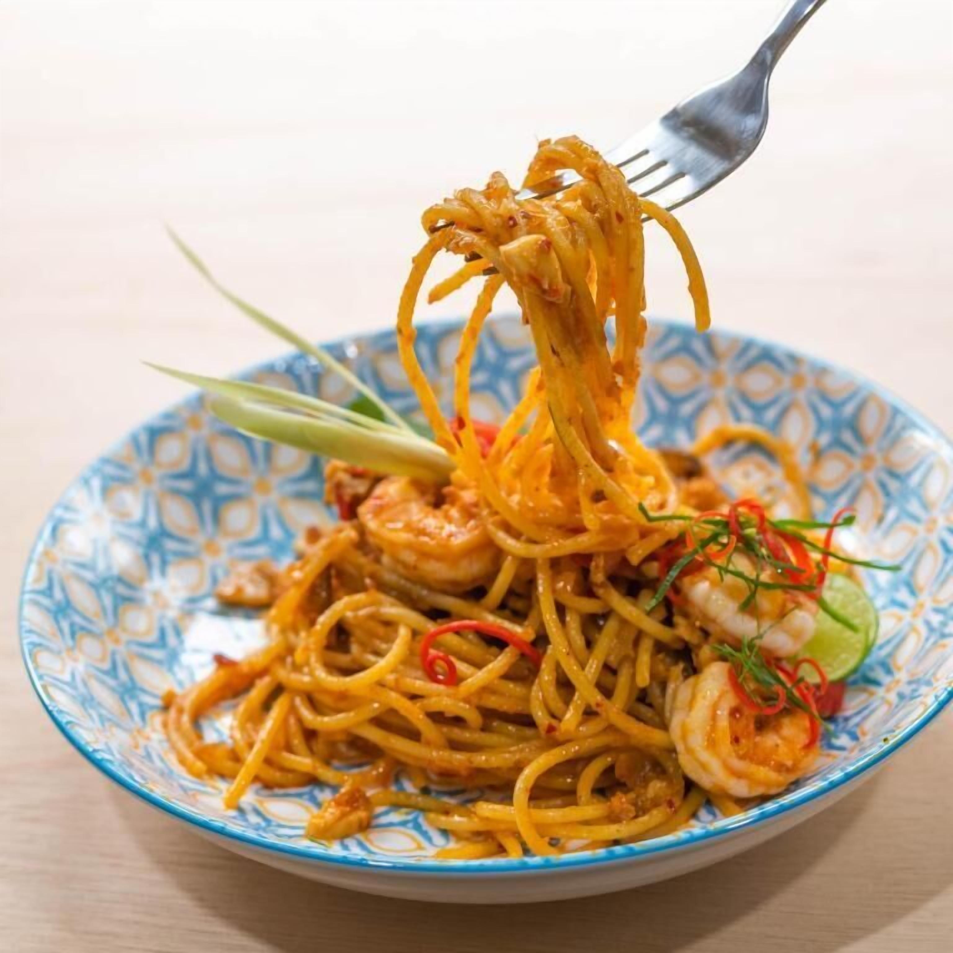 Un plato de espagueti con camarones y guarniciones.