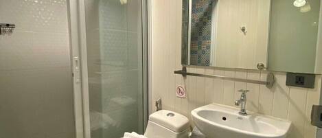 Un baño con inodoro, lavabo y cabina de ducha de vidrio.