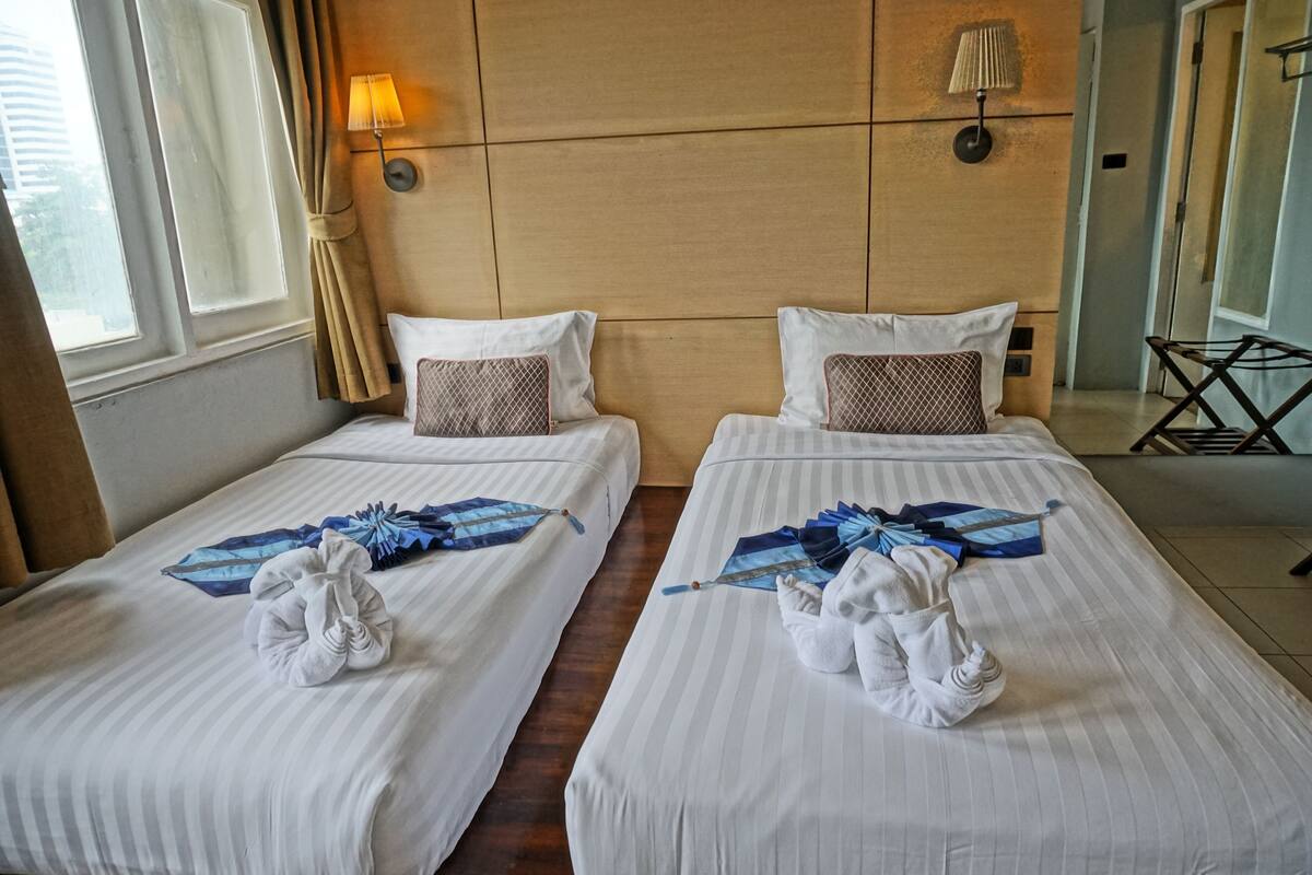 A hotel room with two beds, each with a neatly folded towel and a decorative item.