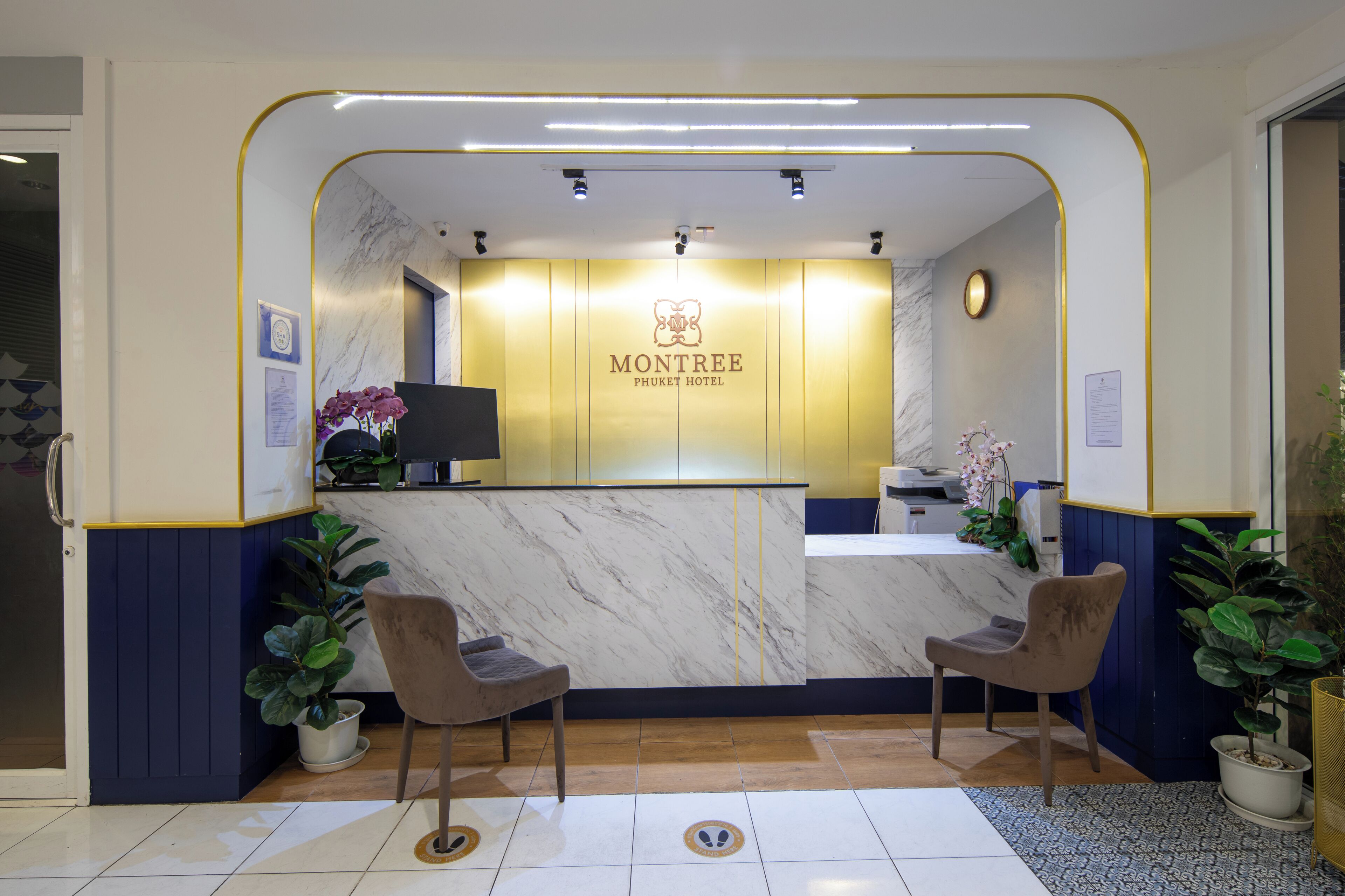 A reception area with a marble counter, two chairs, and potted plants.
