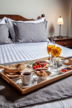 A breakfast tray with bread, cheese, meats, and drinks on a bed. - La Noi Guesthouse (Grevena)