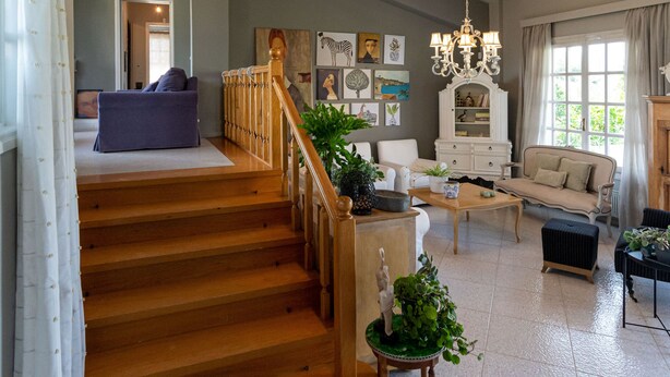 A spacious living area with a staircase, a chandelier, and a variety of furniture including a sofa, armchair, and a wooden coffee table. - Serene Seaside Bliss - Lush & Secluded Garden Oasis (Kalamata)