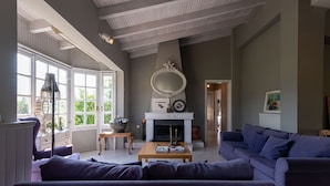 A living room with a fireplace, a large mirror, and a sofa. - Serene Seaside Bliss - Lush & Secluded Garden Oasis (Kalamata)