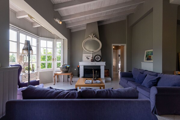 A living room with a fireplace, a large mirror, and a sofa. - Serene Seaside Bliss - Lush & Secluded Garden Oasis (Kalamata)