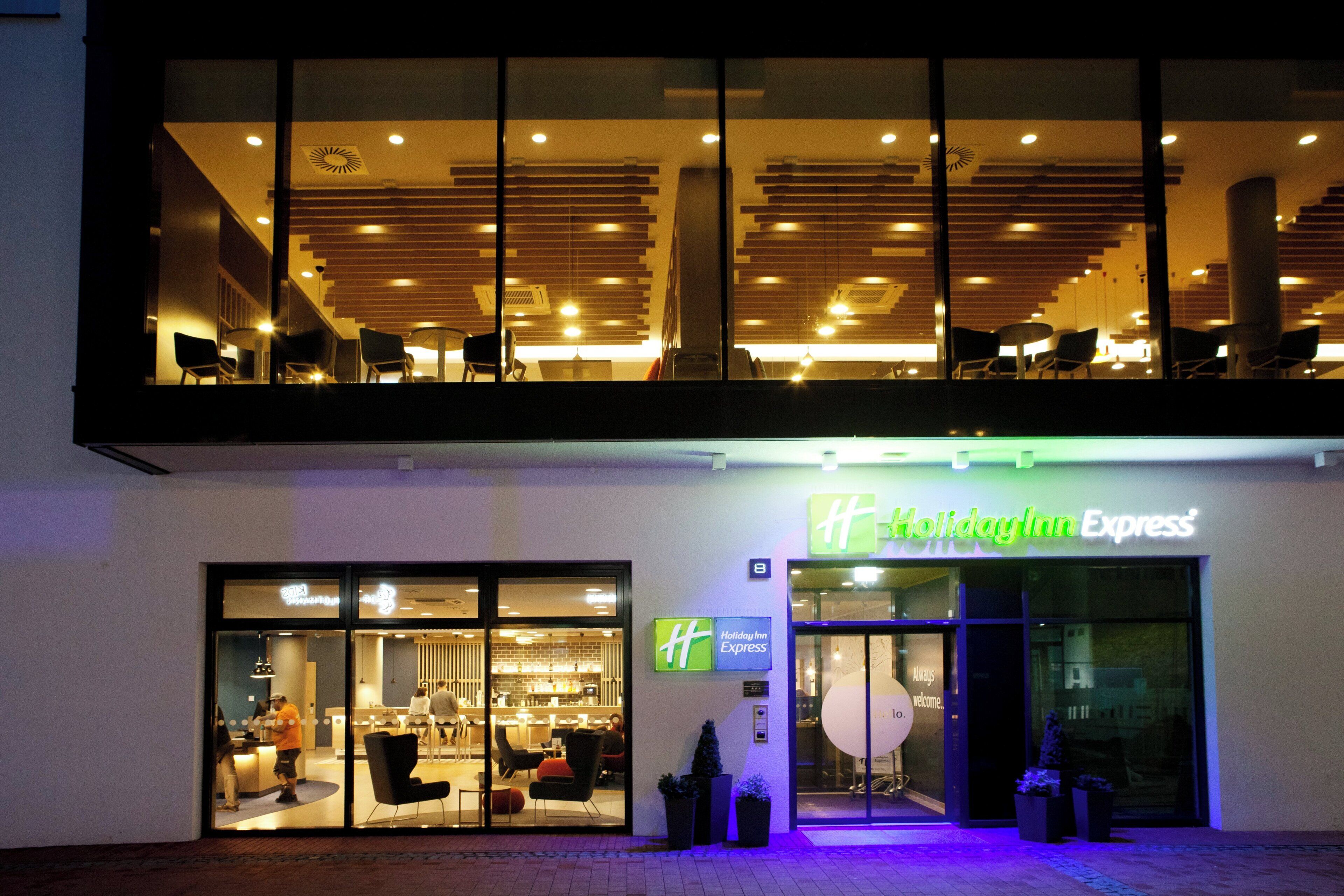 A Holiday Inn Express hotel with a modern interior, large windows, and a visible seating area outside.