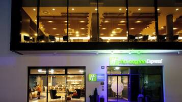 A Holiday Inn Express hotel with a modern interior, large windows, and a visible seating area outside.
