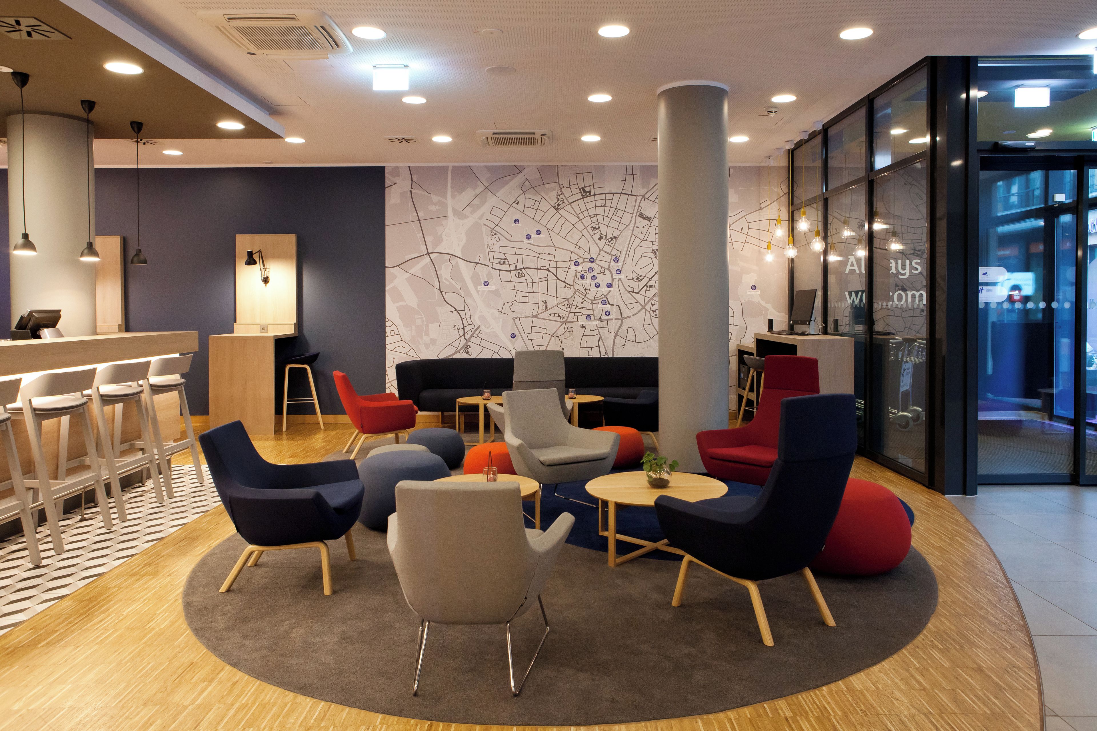 A modern lounge area with a central seating arrangement, a bar counter, and a large map on the wall.