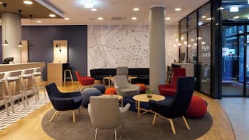 Ein moderner Lounge-Bereich mit einer zentralen Sitzecke, einer Bar und einer großen Karte an der Wand.